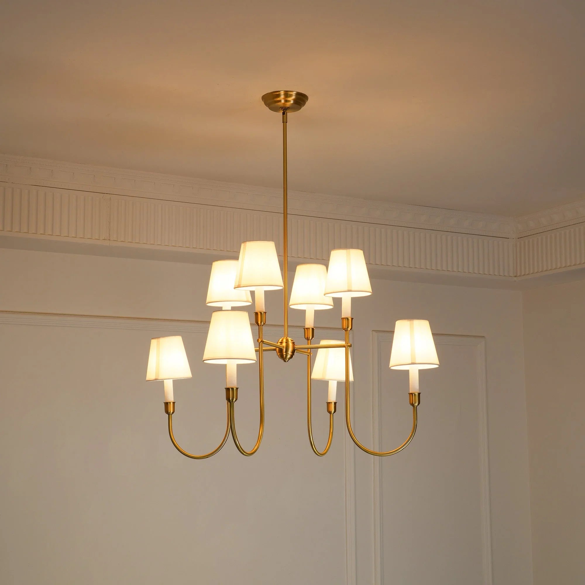 Modern brass chandelier with eight white lampshades hanging in a stylish interior