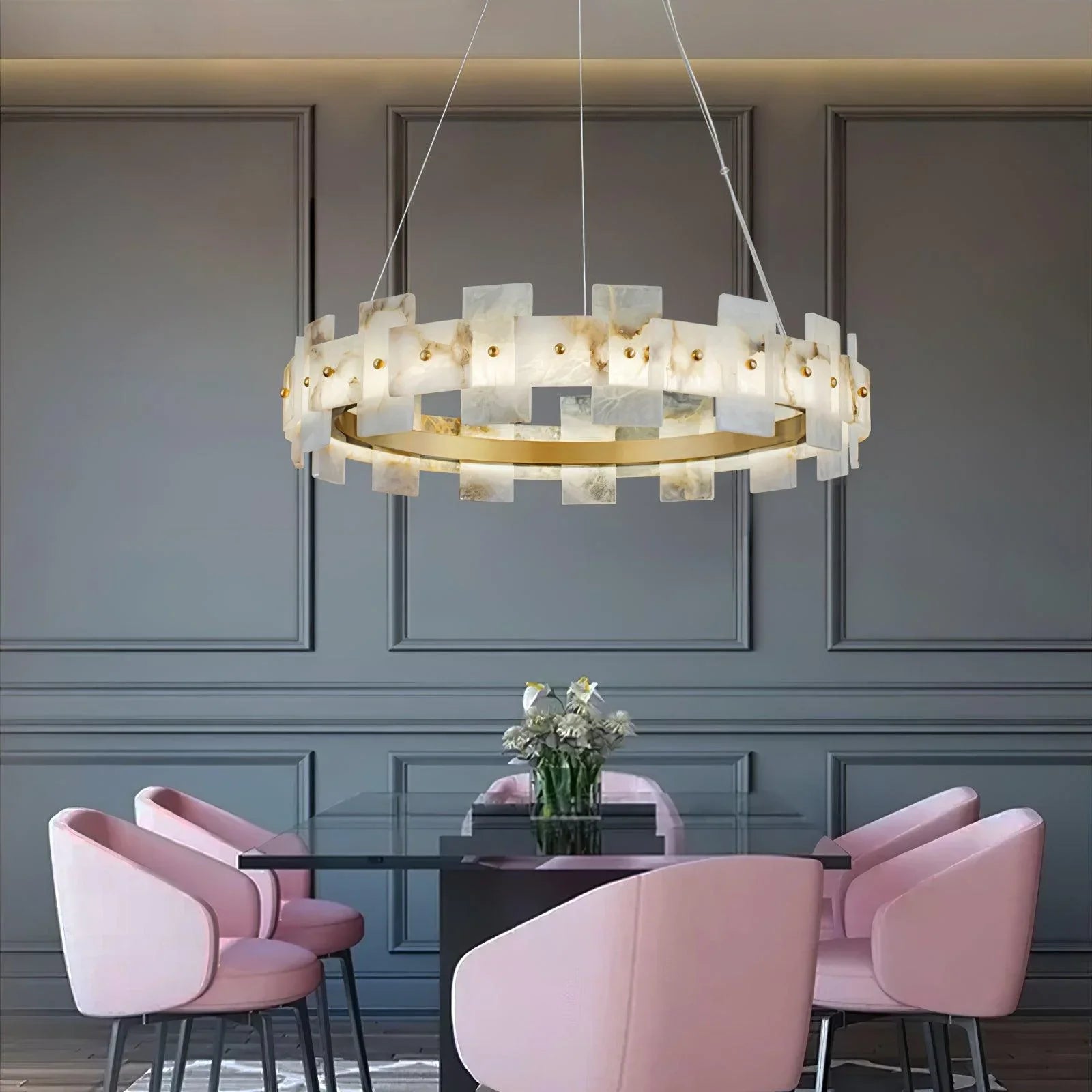 Modern brass and alabaster halo chandelier by YH Lamps above glass dining table with pink chairs