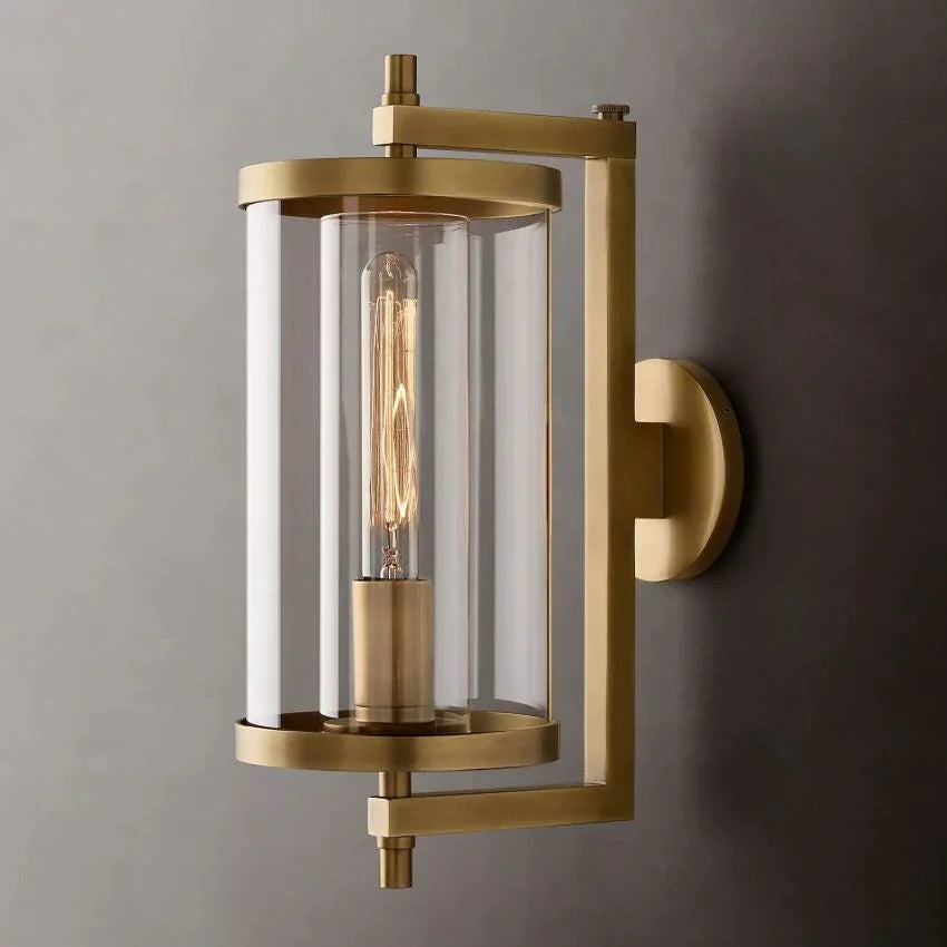 Modern brass wall sconce with glass cylinder and exposed bulb on gray wall, YH Lamps