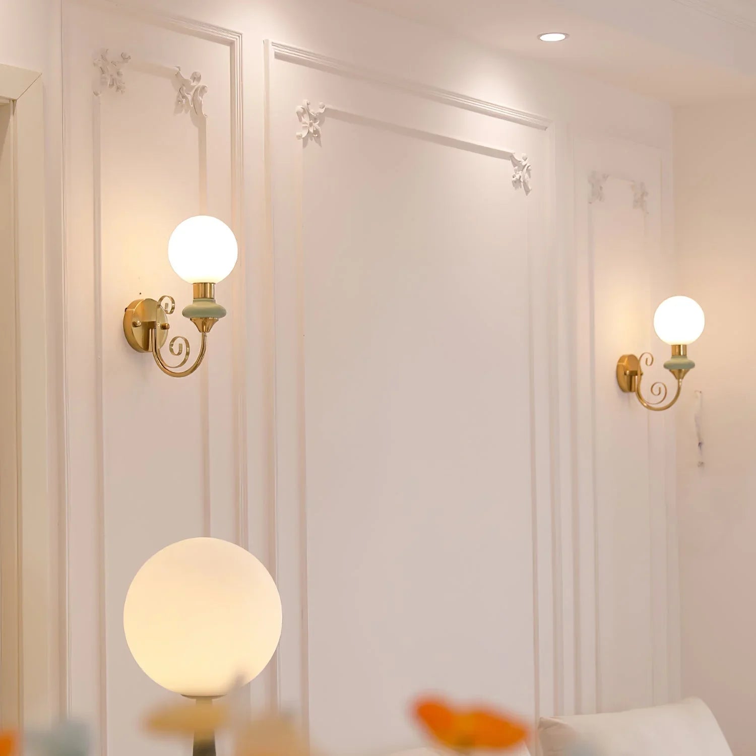 Elegant modern wall sconces with frosted glass globes and gold accents in a bright living room