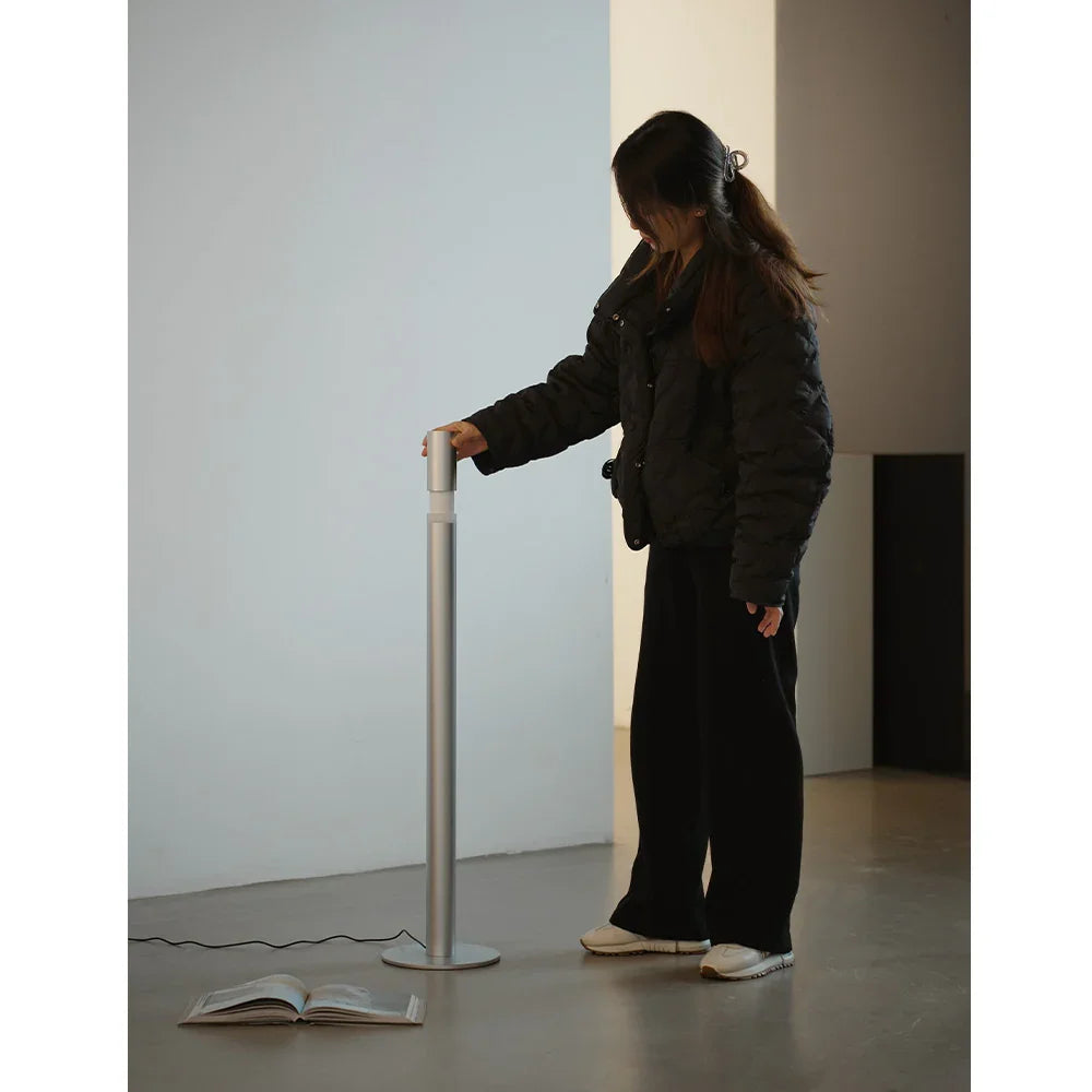 Modern floor lamp in silver finish with person standing beside, minimal interior design