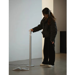 Modern floor lamp in silver finish with person standing beside, minimal interior design