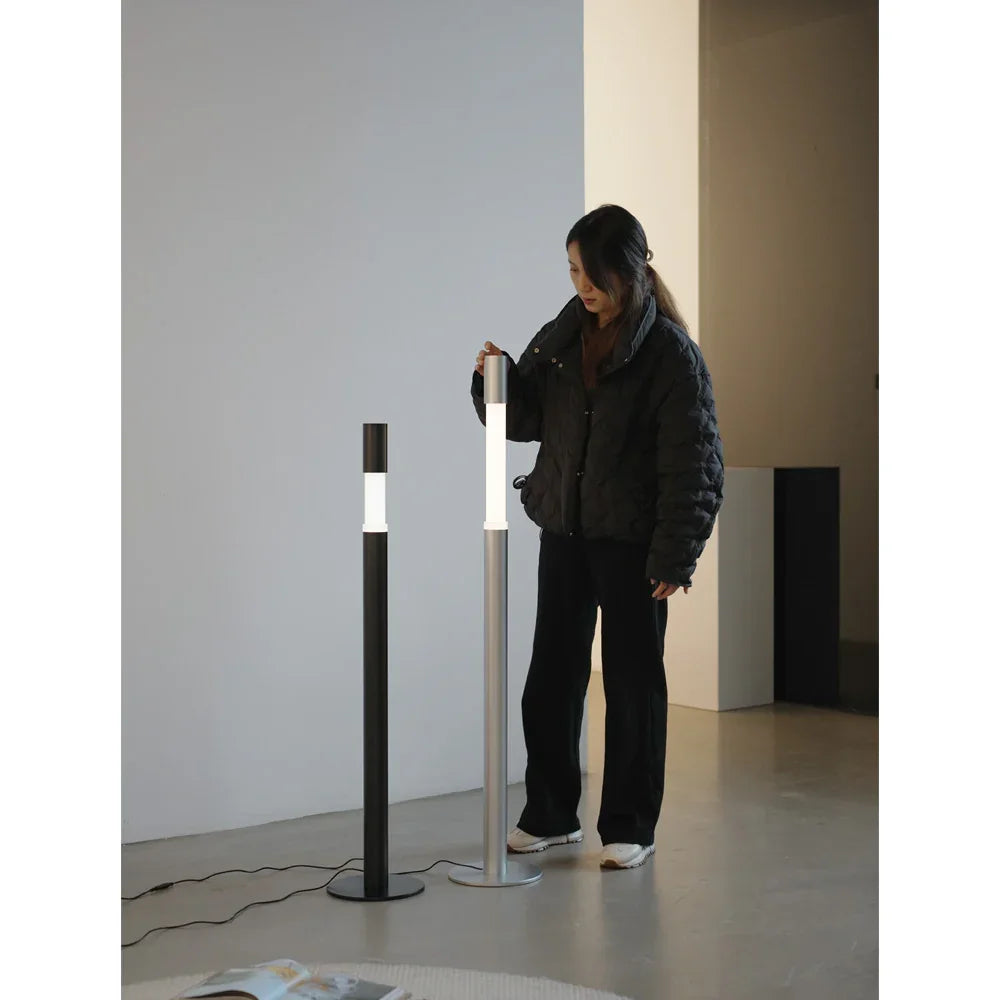 Woman standing beside two modern LED floor lamps in a minimalist living space