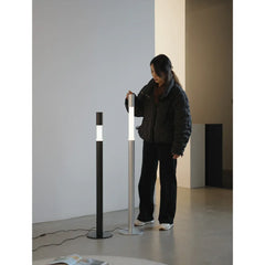 Woman standing beside two modern LED floor lamps in a minimalist living space