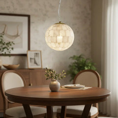 Modern alabaster ball pendant light hanging above wooden dining table with vase and chairs in elegant home interior