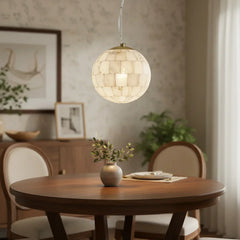 Modern alabaster ball pendant light hanging above wooden dining table with vase and chairs in elegant home interior