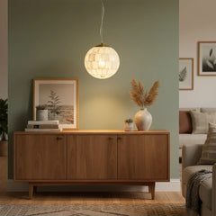 Alabaster ball pendant light glowing above wooden sideboard with framed botanical print and vases in modern living room