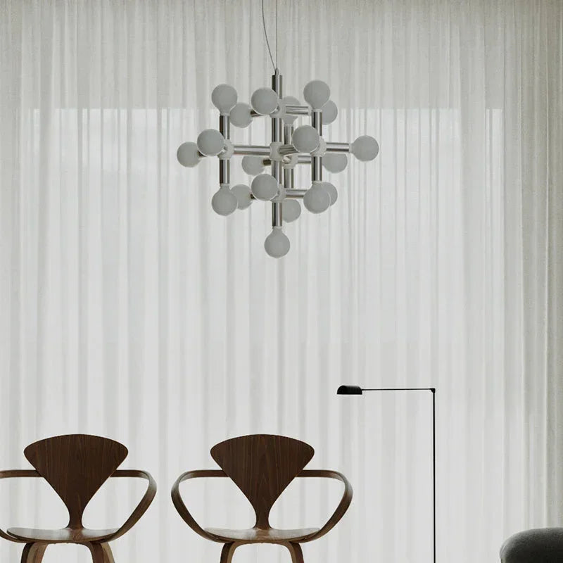 Modern chandelier with globe bulbs above designer chairs in a minimalist living room