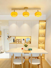 Modern kitchen with pumpkin-shaped yellow ceiling lamp, wooden dining set, and built-in shelving