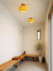 Yellow wood color pumpkin ceiling lamps in modern hallway with wooden bench and potted plant