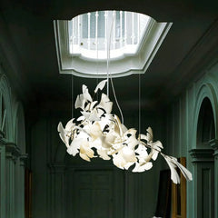 Modern gold and white ginkgo leaf chandelier hanging in elegant hallway with skylight