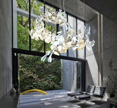 Modern living room with floor-to-ceiling windows, green wall, gray chairs, and white ginkgo chandelier