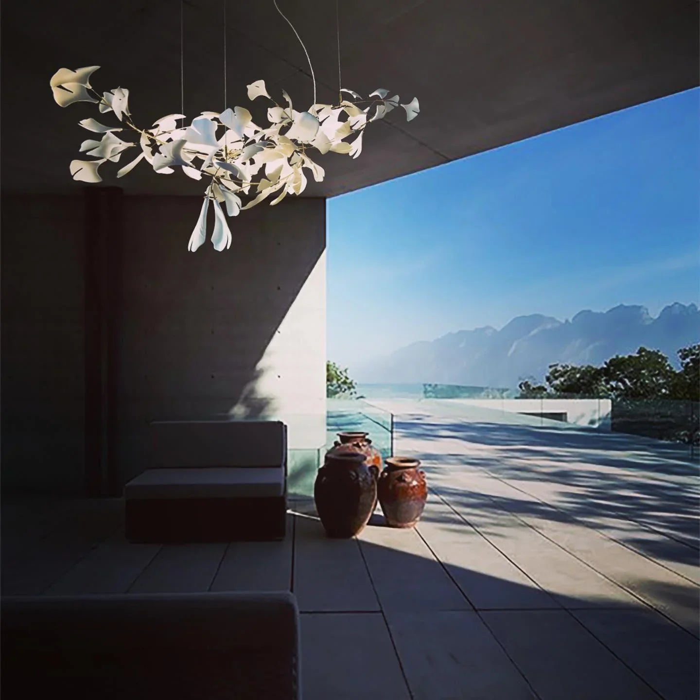 Modern white gingko leaf chandelier hanging in a minimalist patio with mountain view and terracotta pots