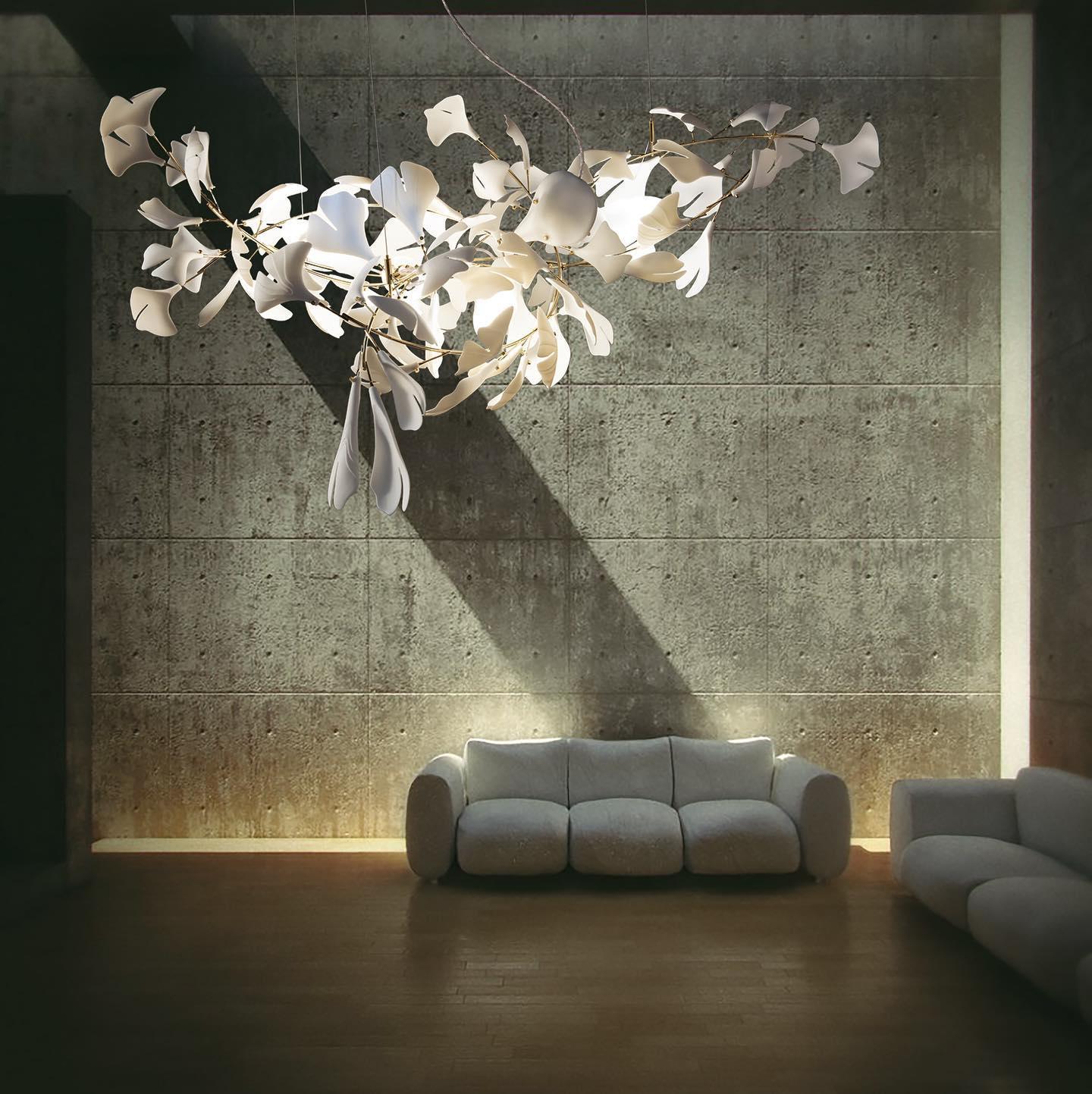 Modern living room with textured concrete wall, cozy white sofa, and elegant white and gold ginkgo chandelier
