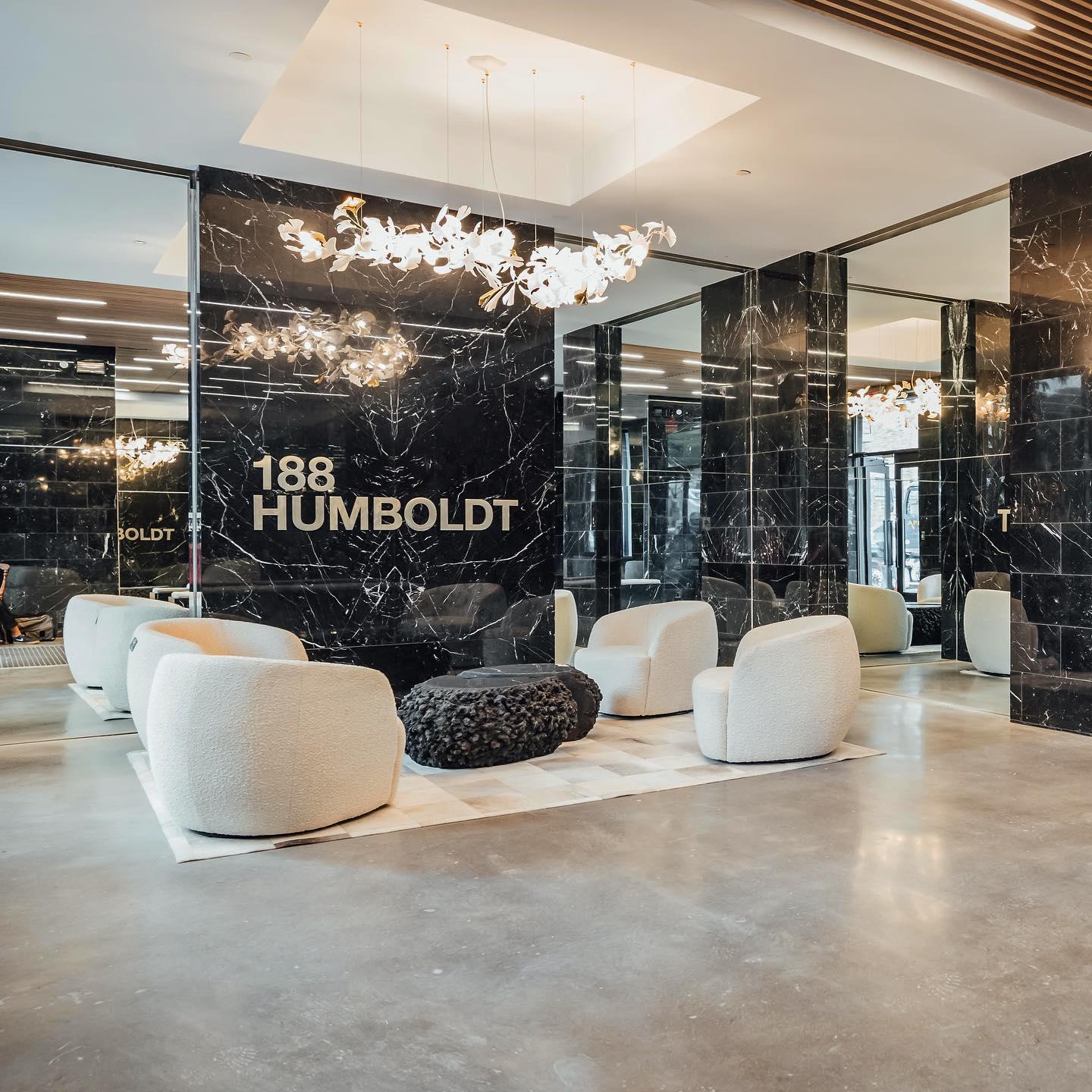 Modern lobby with white curved armchairs, black textured coffee table, and gold-white gingko chandelier