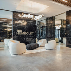 Modern lobby with white curved armchairs, black textured coffee table, and gold-white gingko chandelier