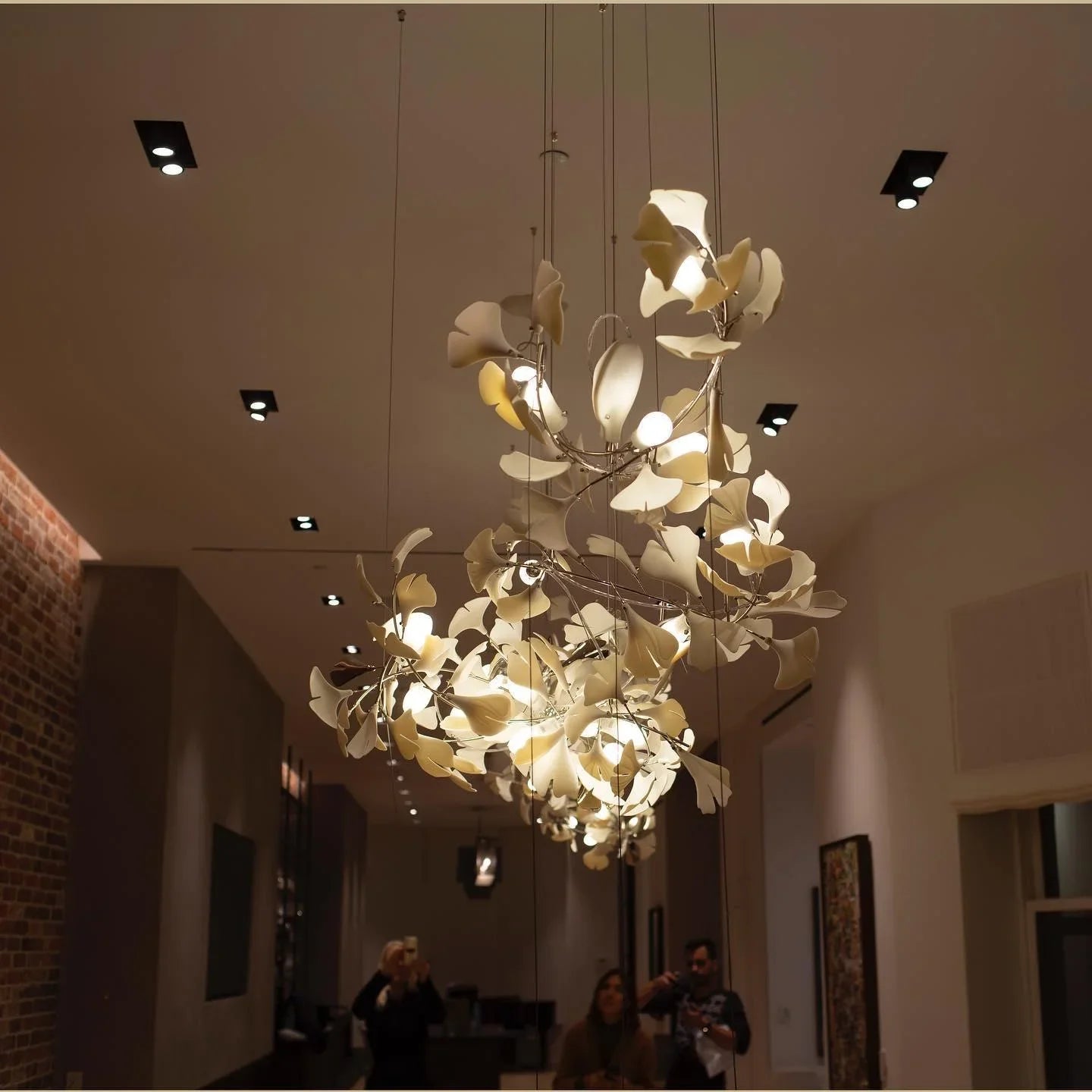 Modern gold and white ginkgo leaf chandelier with multiple bulbs hanging in stylish indoor space