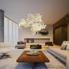 Modern living room featuring a white and gold gingko leaf chandelier above a wooden coffee table with stone decor.