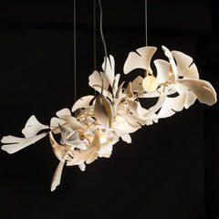 Modern gold and white Gingko leaf chandelier with multiple lights suspended against a black background