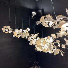 Modern gold and white Gingko leaf chandelier with multiple illuminated branches against a dark background