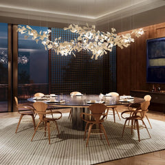 Modern dining room with round table, wooden chairs, and white gold gingko leaf chandelier lighting