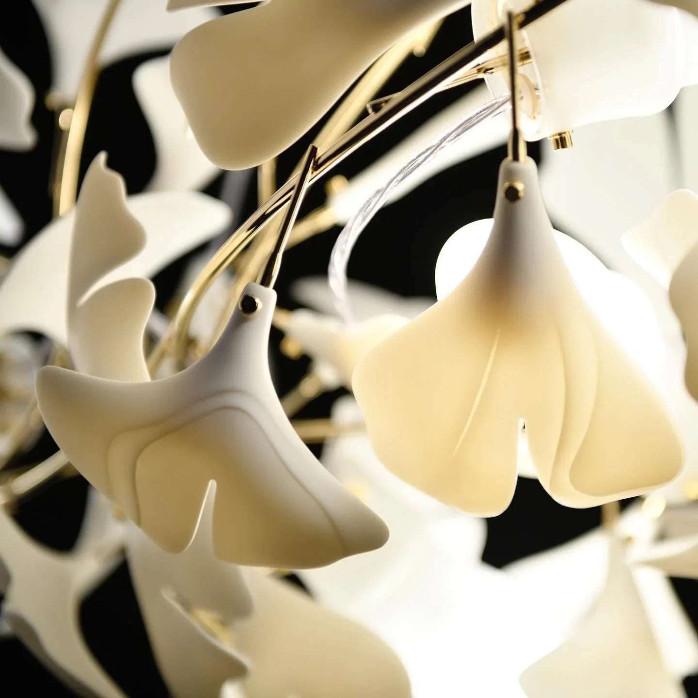 Close-up of elegant gold and white Gingko leaf chandelier with soft glowing light bulbs