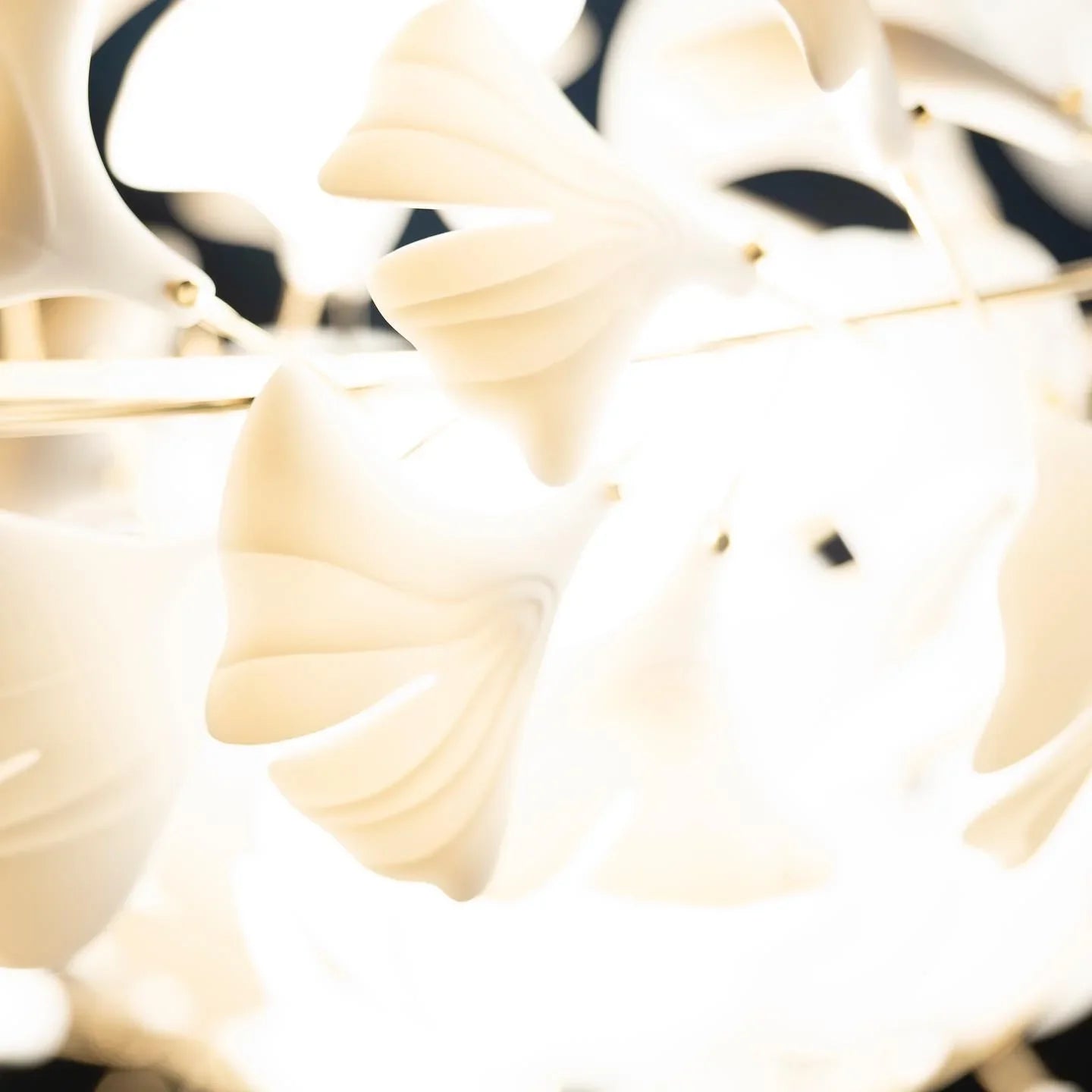 Close-up of modern gold and white ginkgo leaf chandelier with soft glowing light petals
