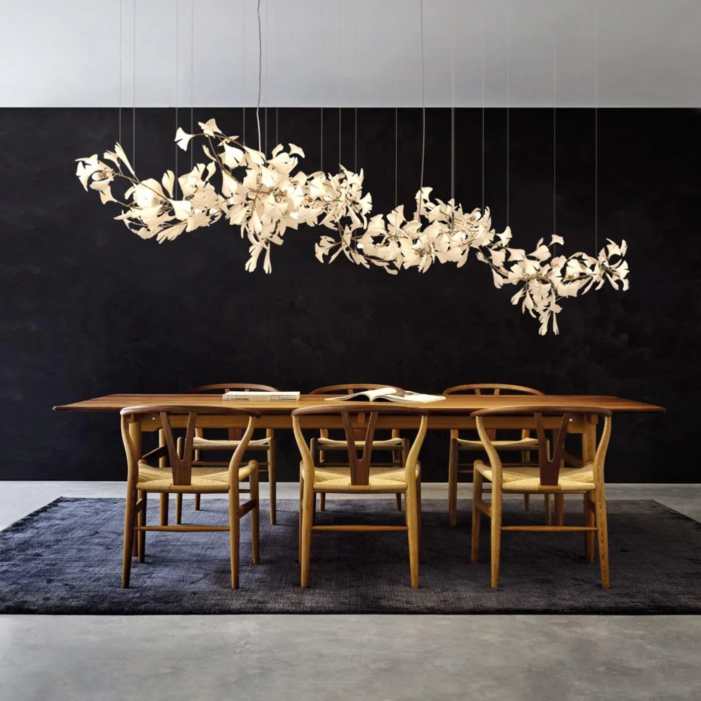 Modern gold and white Gingko leaf chandelier above wooden dining table with six chairs on dark rug