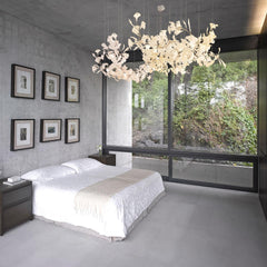 Modern bedroom with concrete walls, large window, dark wood nightstands, and white gold gingko chandelier