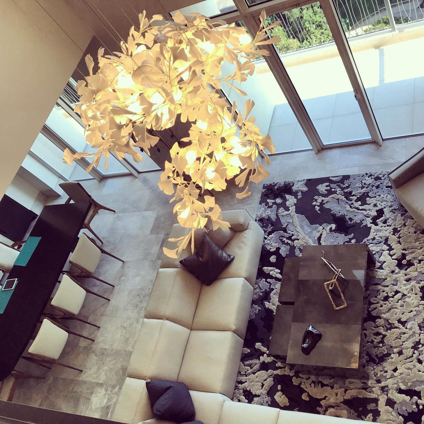 Modern living room with gold white gingko chandelier over beige sectional sofa and decorative rug