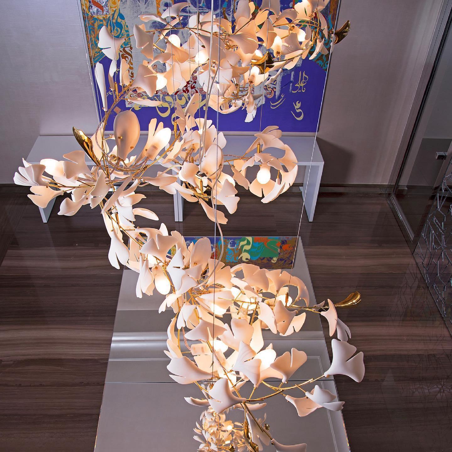 Modern gold and white Gingko chandelier with delicate leaf design hanging in stylish interior