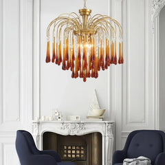 Modern chandelier with brass frame and amber glass droplets hanging above white ornate fireplace in elegant living room
