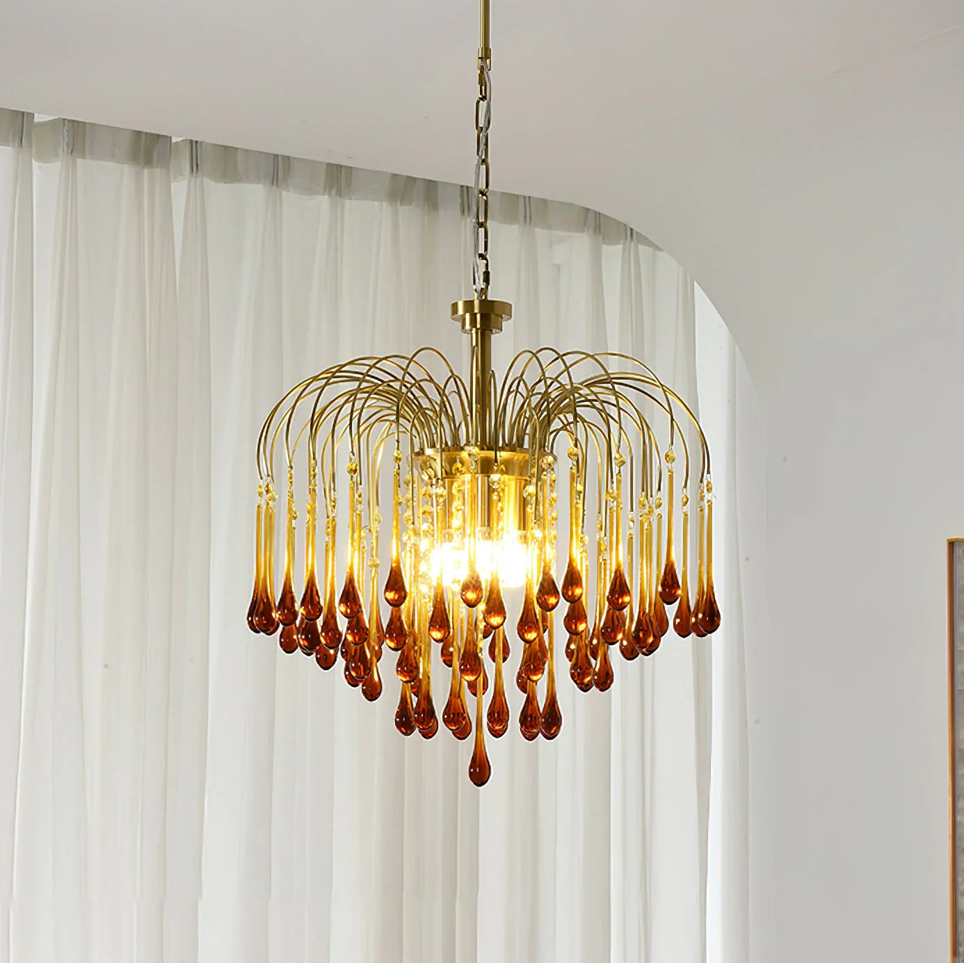 Modern brass chandelier pendant lamp with amber glass droplets hanging in a stylish room