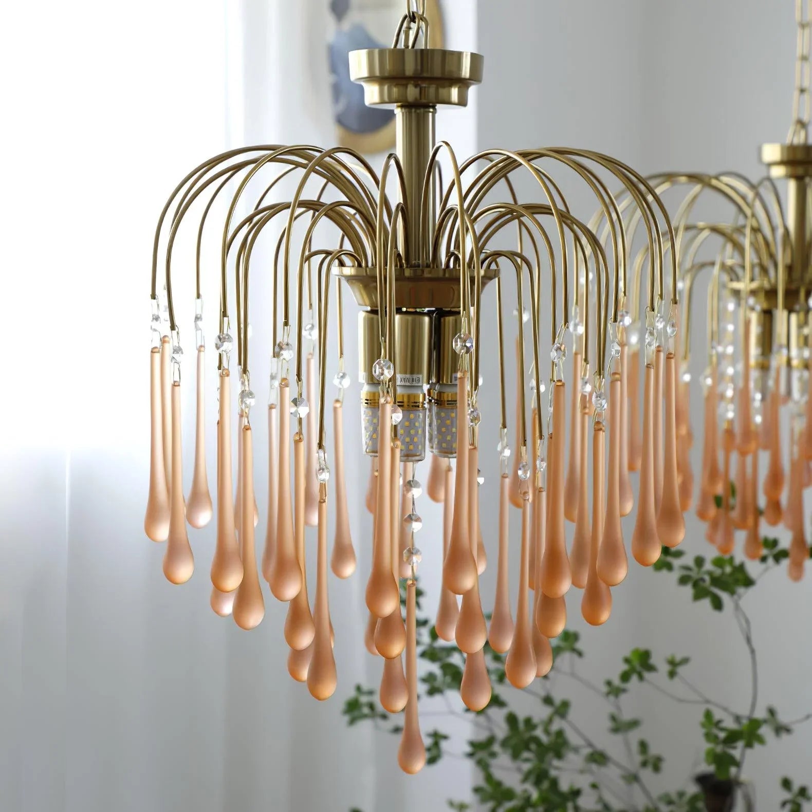 Modern brass chandelier with clear and maltose glass teardrop pendants hanging in bright indoor room
