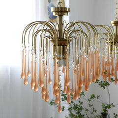 Modern brass chandelier with clear and maltose glass teardrop pendants hanging in bright indoor room