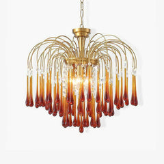 Modern brass chandelier with amber glass teardrop pendants and crystal accents hanging from curved arms