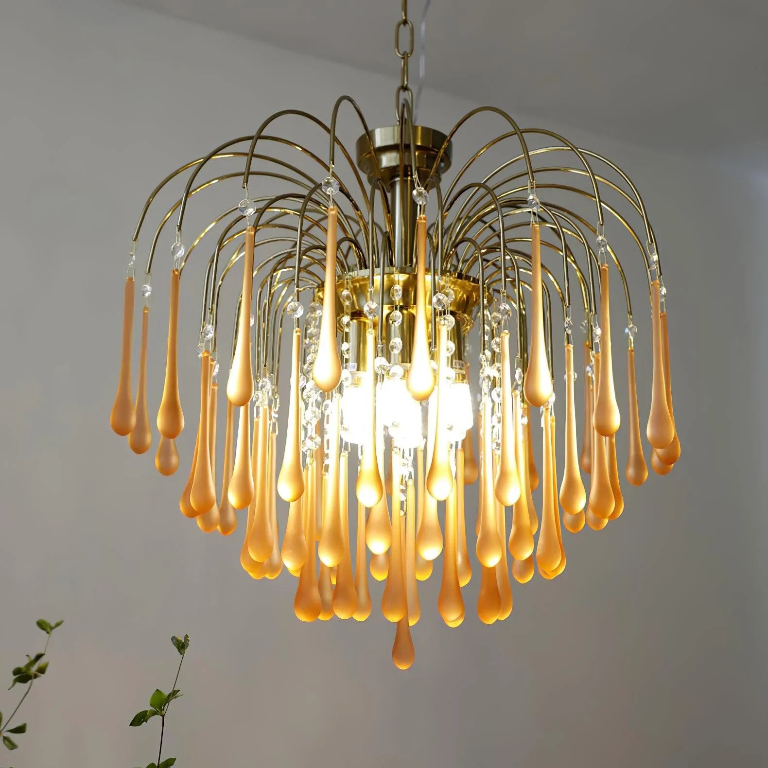 Modern brass chandelier with amber teardrop glass pendants and crystal accents hanging indoors