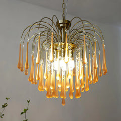 Modern brass chandelier with amber teardrop glass pendants and crystal accents hanging indoors