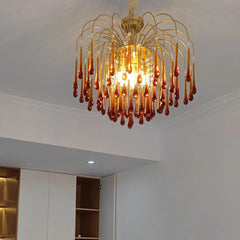 Modern YhLamps brass chandelier with amber glass droplets hanging on curved rods, illuminating bright room