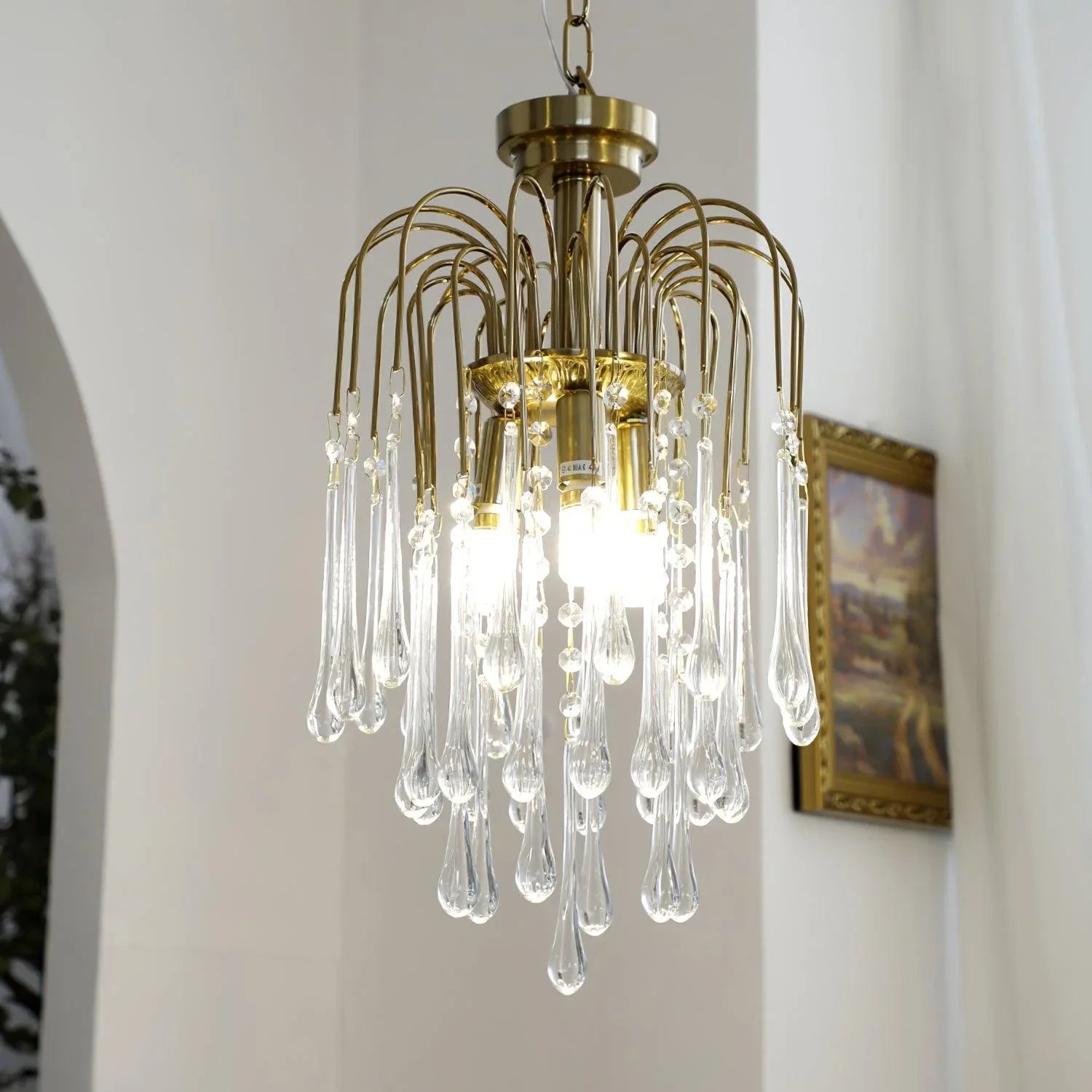 Modern brass chandelier with clear maltose crystal teardrop pendants hanging in bright interior