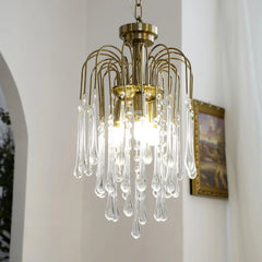 Modern brass chandelier with clear maltose crystal teardrop pendants hanging in bright interior
