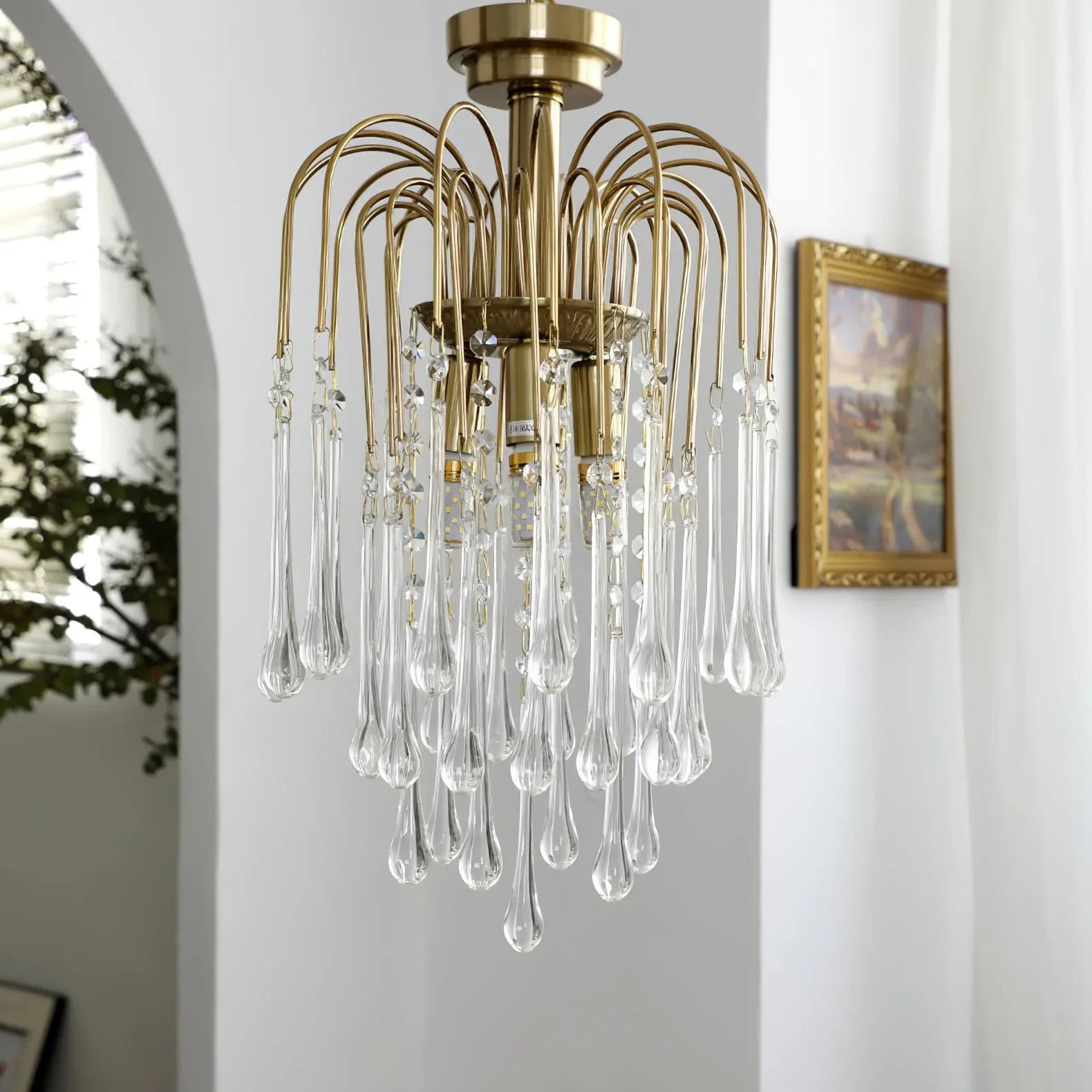 Modern brass chandelier pendant lamp with clear crystal glass droplets in a bright room