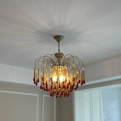 Modern brass chandelier with amber glass droplet accents hanging from ceiling in elegant room
