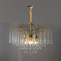 Modern brass chandelier with clear glass teardrop pendants hanging from curved arms, elegant pendant lamp