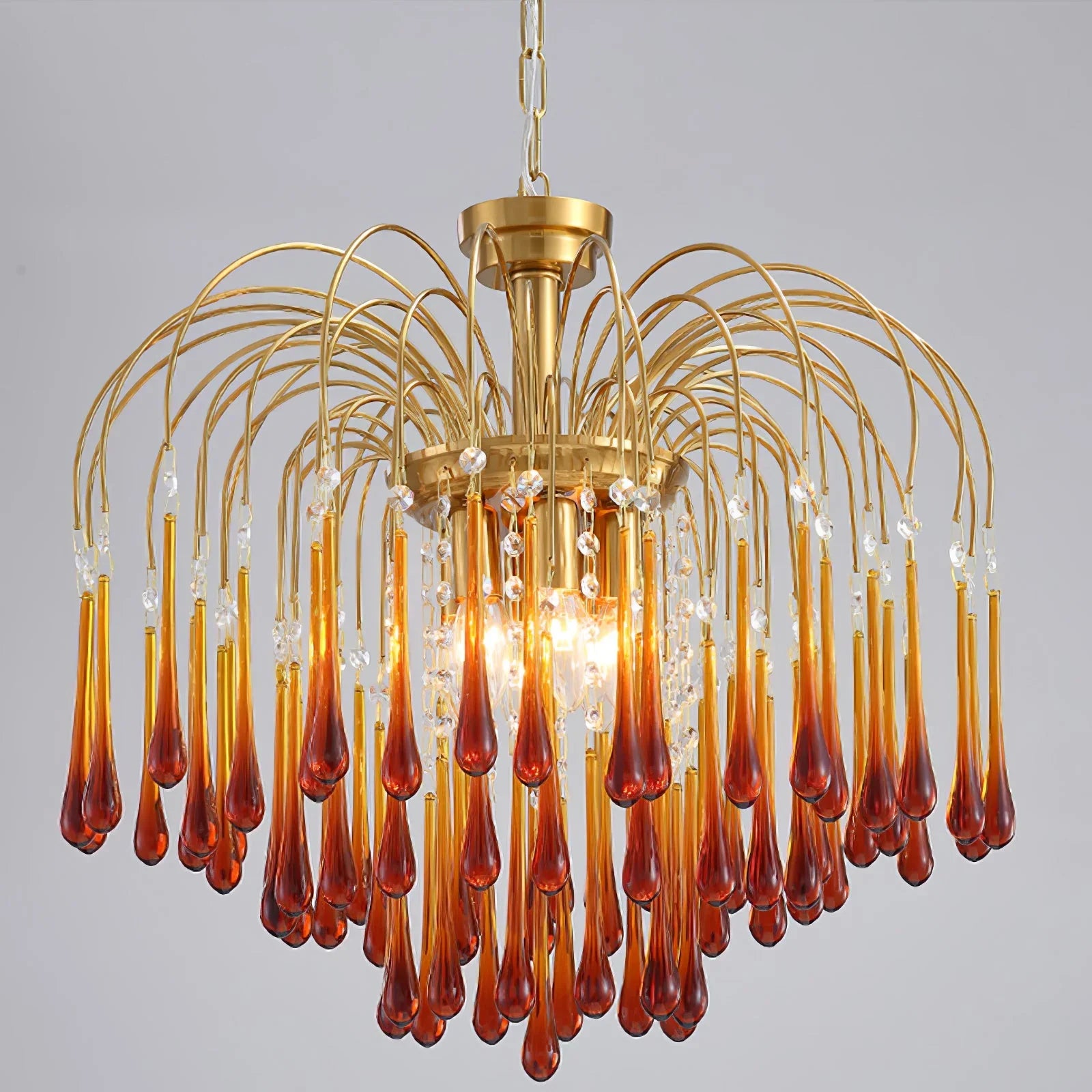 Modern brass chandelier with amber glass teardrop pendants and crystal accents, elegant lighting fixture