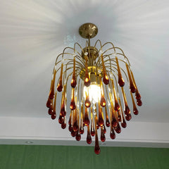 Modern brass chandelier pendant lamp with amber glass teardrops and clear crystals lighting a ceiling