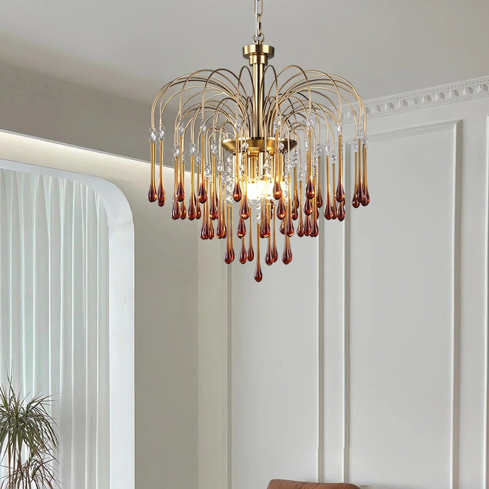 Modern brass chandelier with hanging amber glass teardrops in elegant living room at YhLamps
