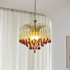 Modern brass chandelier pendant lamp with amber glass droplets hanging in bright room