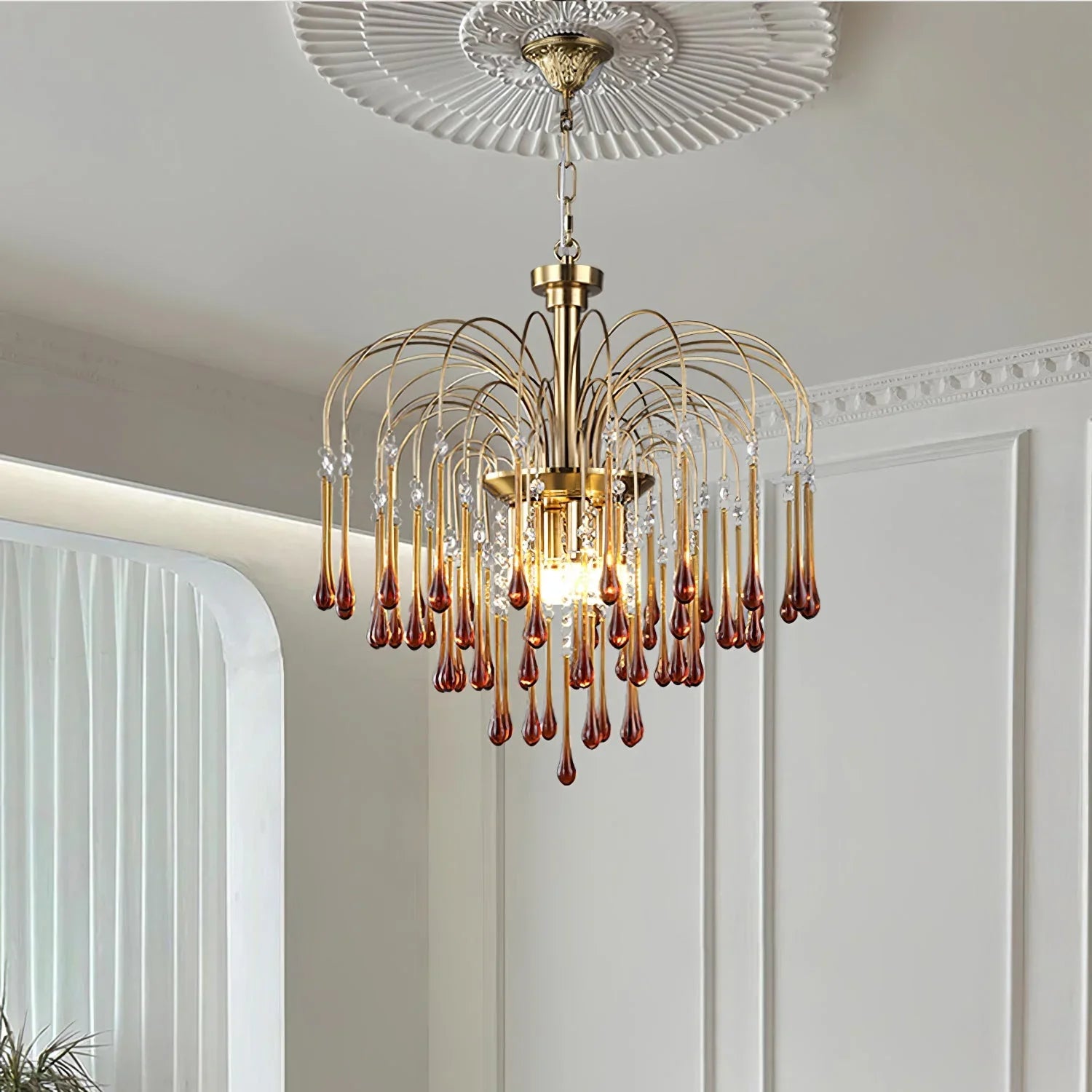 Modern brass chandelier with amber glass droplets, elegant pendant lamp in stylish white room