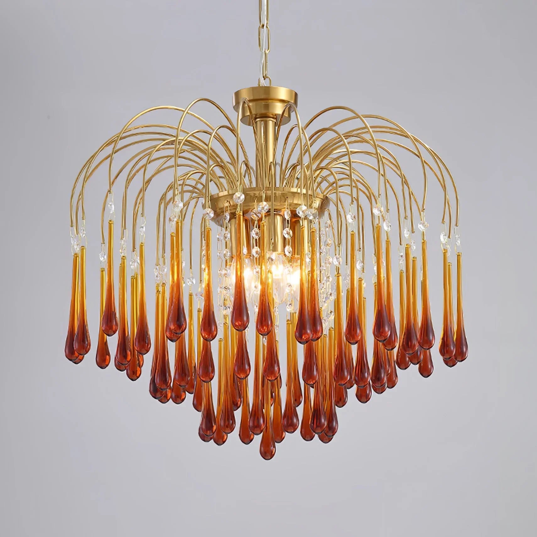 Elegant modern chandelier with brass frame and amber maltose glass drops, illuminated pendant light